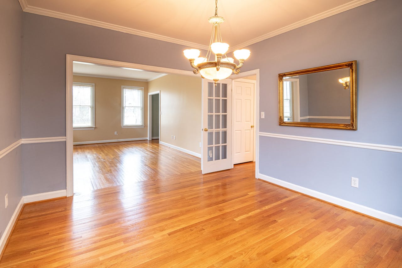 Bright residential room with hardwood floor and chandelier, ideal for real estate listings.