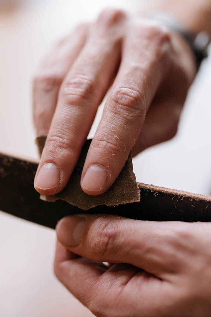 Detailed close-up shot of hands using sandpaper to smoothen a wooden surface, highlighting craftsmanship.